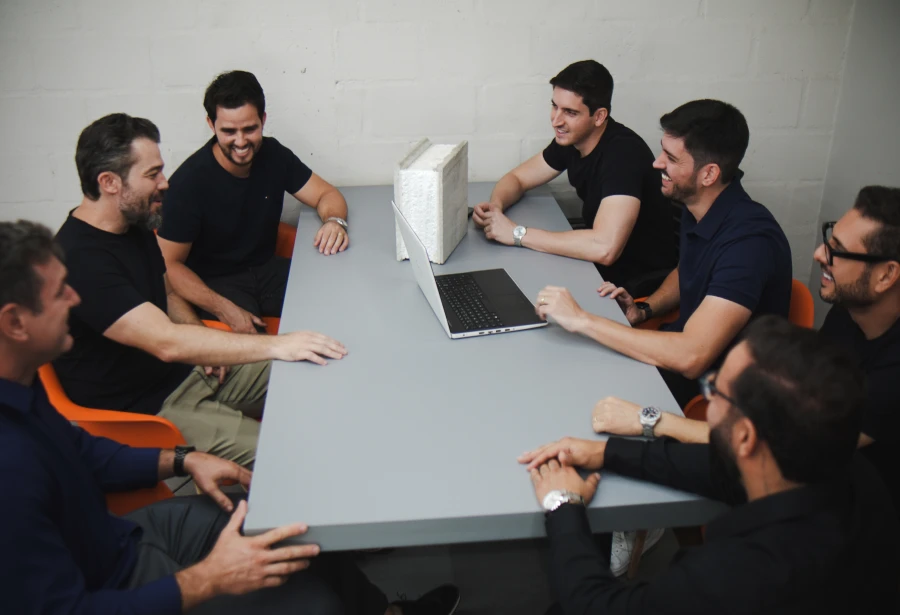 Equipe reunida em mesa de reunião analisando projeto imobiliário e planejamento de empreendimentos
